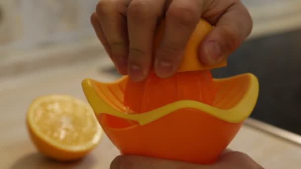 A man squeezes the juice from an orange on a manual juicer — Stock Video