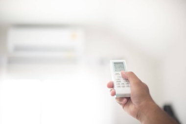 Klima için uzaktan kumanda kullanan bir adam eli. 25 derece santigrat derecedeki havanın sıcaklığını kontrol et. Hava atmosferini dengele. Enerji tasarrufu kavramı