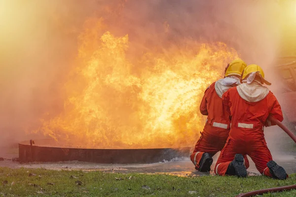 Two brave firefighter using extinguisher and water from hose for fire fighting, Firefighter spraying high pressure water to fire, Firefighter training with dangerous flames, Copy space