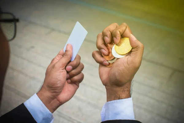 Right hand of business man show a handful of a gold coin and left hand holding a credit card. It is  feeling so stresseds. Money, Financial crisis. Business and finance concept.