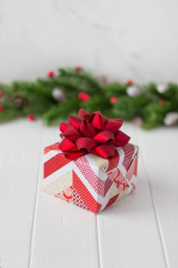 Kırmızı beyaz kağıt hediye ve arka planda köknar dalları ve beyaz bir masada kırmızı böğürtlen.