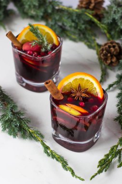 Elma, portakal ve tarçınlı Glintwein beyaz bir zemin üzerinde Noel ağacı dallarının arka planına karşı