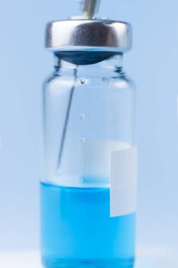 İçinde şırınga olan mavi bir aşı şişesi.