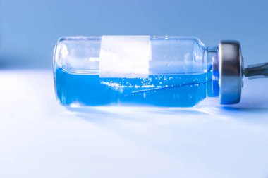 İçinde şırınga olan mavi bir aşı şişesi.