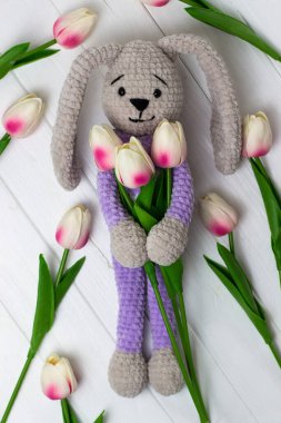 Beyaz ahşap arka planda laleleri olan oyuncak tavşan örmüştü. Yukarıdan görüntüle