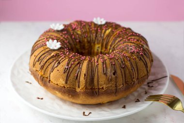 Ev yapımı hamur işleri. Portakallı kek ve çikolatalı ganache ve beyaz papatyalarla süslenmiş şekerli meyve.