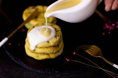 Siyah arka planda ekşi kremalı cheesecake. Peynirli kekler konsantre süt döktü. Siyah levha. Yandan görüntüle.