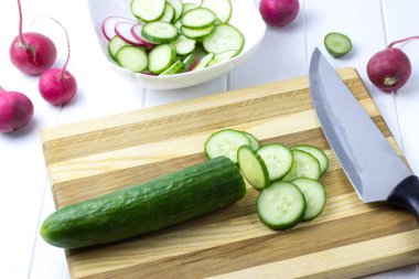 Salatayı hazırlama süreci. Tahtada salatalık kesmek. Salatalık, turp ve ıspanaktan salata. Yan görünüm