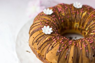 Ev yapımı hamur işleri. Portakallı kek ve çikolatalı ganache ve beyaz papatyalarla süslenmiş şekerli meyve.