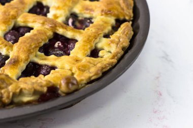 American cherry pie in baking dish on a white background