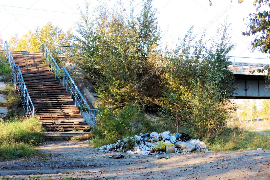    garbage, large garbage pile on the river bank near the bridge,  degraded garbage. Pile of stink and toxic residue. Consumer society Cause massive waste.       