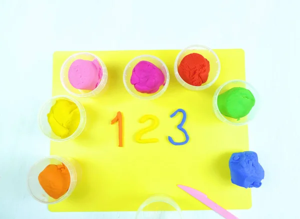         Renkli plastik kaplar ve çocuk bir, iki, üç numara yaptı. beyaz tahta arkaplan 