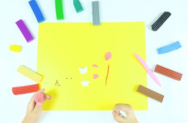 Çocuğun elleri plastikten pembe beyaz kedi yapar. Adım adım talimat. Adım 1