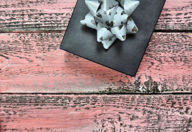 Siyah siyah tebrik kartı modeli, üzerinde siyah hediye kutusu olan pembe eski ahşap masa, tasarım için web pankartı, genellikle doğum günü, yıldönümü hediyeleri, hediye kartları için kullanılır. Kırsal biçim 