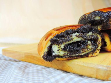 Tahta bir yüzeyde haşhaş tohumu rulosu, yakın çekim, seçici odaklanma          