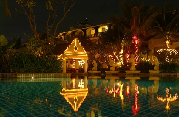 Vista Nocturna Palmeras Guirnaldas Brillantes Reflejaba Luces Superficie Del Agua —  Fotos de Stock