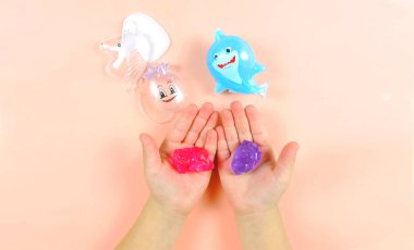 Komik oyuncakların kutularındaki renkli sümükler, sümüklerle oynayan bir çocuk.