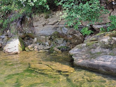  Suyun altından kayanın dik kıyı dokusu, yüksek uçurum. Suda yolculuk, nehir kıyısında dinlenme, şehirden uzakta dinlenme, güzellik doğası, sahil boyunca yer alan kayaların yüzeyi.         