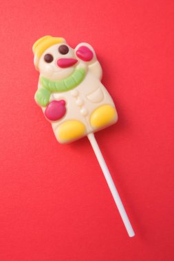  Şekerden yapılmış kardan adam. Mutlu Noeller ve mutlu yıllar tebrik kartı. Komik Kardan Adam Noel hediyesinin lolipopları. Kırmızı arkaplan         