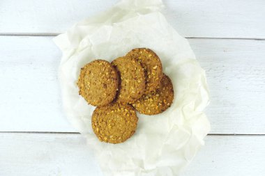 Beyaz kağıtta yulaf ezmeli kurabiye, ahşap beyaz arka plan