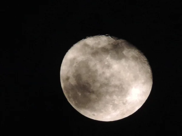 the full moon with dark spots on the black sky