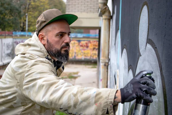 Graffiti sanatçısı iş başında, duvara sprey boyayla resim çiziyor. Sokak sanatı kültürü kavramı.