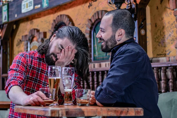 Two male friends drinking whiskey and beer together at the pub. They are drunk and they are talking, comforting each other. Problems with alcohol.