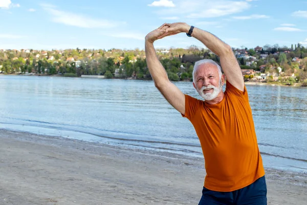 Щасливий Енергійний Старший Чоловік Пенсії Тягнеться Пляжі Роблячи Бічні Вправи — стокове фото