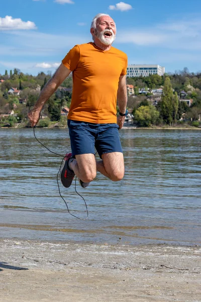 Active Senior Elderly Man Jumping Rope Exercising Beach Riverbank Motion — Stock Photo, Image