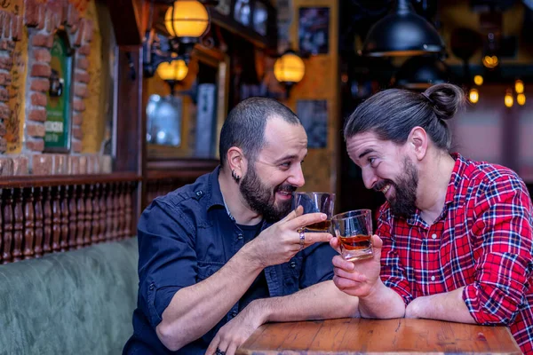 İki neşeli erkek arkadaş birlikte takılıyor, gülüyor, kadeh kaldırıyor ve barda viski içiyor. Hayatı kutluyoruz..