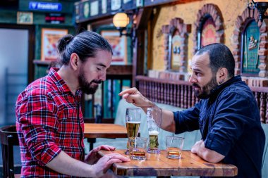 İki erkek arkadaş barda viski ve bira içiyor. Mutlu ve sarhoşlar ve birbirleriyle konuşuyorlar. Hareket bulanıklığı.