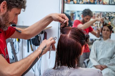 Genç bir bayan müşterinin kuaförde ya da kuaförde saçını profesyonel bir kuaföre kestirmesi. Islak saçı düzenleyen bir makasla..