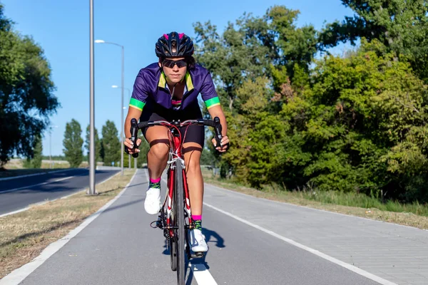 Dışarıda bisiklet süren bir kadın bisikletçi. Spor Kadınlar Bisiklet Yarışması. Yüksek hızda yarışıyorlar. Sağlıklı yaşam tarzı kavramı. Hareket bulanıklığı. Ön görünüm.