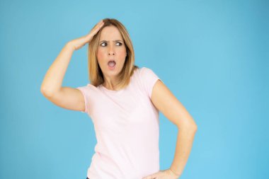 Mavi arka planda tek başına duran heyecanlı genç bayanın görüntüsü.