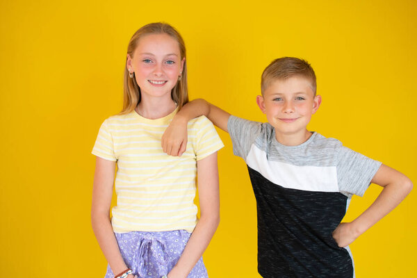 Счастливые брат и сестра обнимают друг друга на желтом фоне.