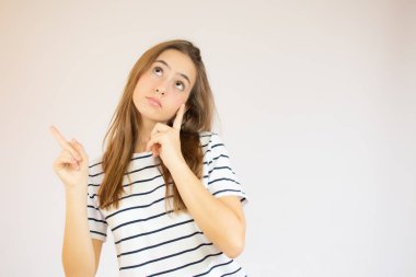 Kırmızı çizgili tişört giymiş mutlu genç bir kızın portresi beyaz arka planda izole edilmiş fotokopi alanını işaret ediyor.