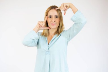 Mutlu kadın beyaz arka planda parmakları izole bir çerçeve yapıyor.