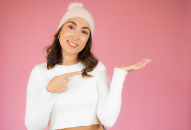 Parmakla işaret eden gülümseyen kadın. Pembe üzerine izole edilmiş portre..