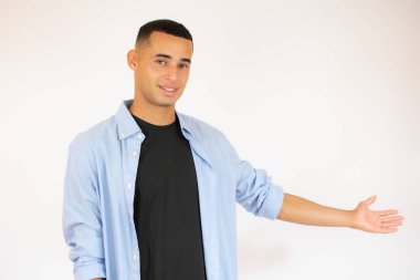 Dost canlısı genç adam kendi tarafını gösterip kameraya bakıyor. beyaz arkaplanda izole