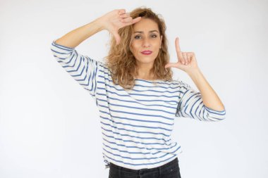 Mutlu kadın beyaz arka planda parmakları izole bir çerçeve yapıyor.