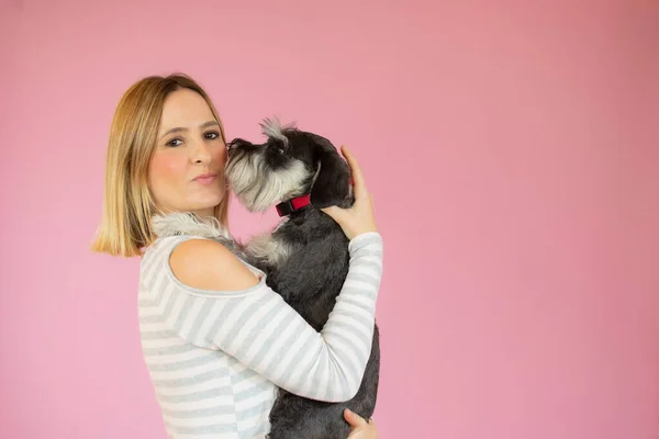 可爱的年轻女人拥抱着她的小狗雪纳犬 主人和狗之间的爱 被蓝色背景隔离了工作室肖像 — 图库照片