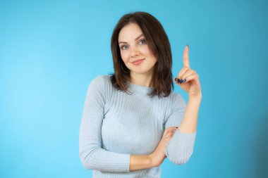 Mavi arka planda parlayan güzel genç bir kadının portresi.