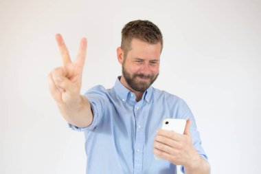 Yakışıklı, mutlu, sıradan adam telefonda konuşurken zafer işareti yapıyor.