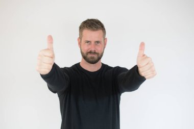 Beyaz arka planda başparmak gösteren mutlu yakışıklı adam..