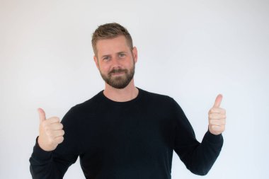 Beyaz arka planda başparmak gösteren mutlu yakışıklı adam..