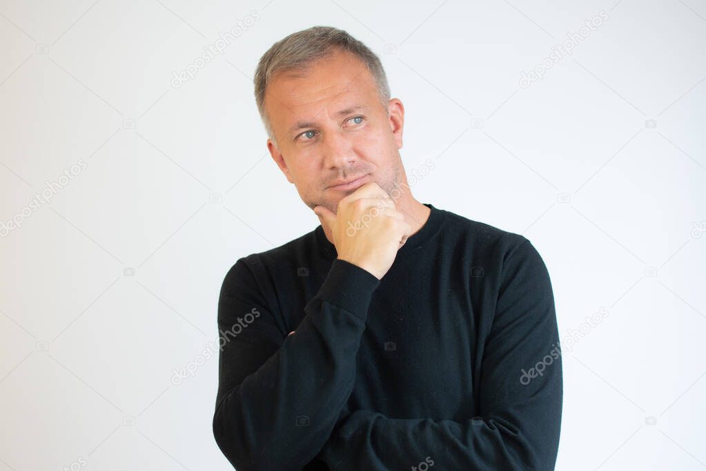 Young man in casual black sweater thinking over white background.