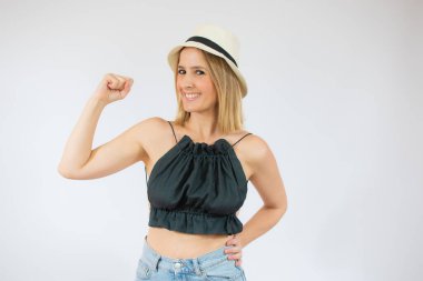 Hasır şapka takan genç ve güzel bir kadın güçlü bir jest yapıyor beyaz soyutlanmış arka planda gülümsüyor..