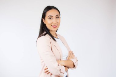 Gülümseyen neşeli bir iş kadınının portresi beyaz arka planda kollarını kavuşturmuş bir şekilde duruyor.