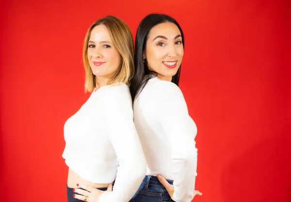 Due Belle Donne Posa Sorridente Con Maglione Bianco Sfondo Rosso — Foto Stock