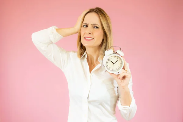 Portrett Smilende Ung Forretningskvinne Som Bekymret Holde Vekkerklokke Isolert Rosa – stockfoto